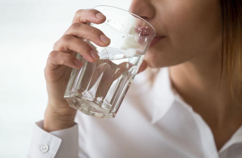 A close-up of a woman drinking water in a glass.