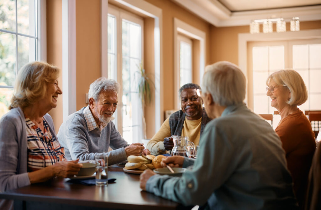A group of seniors sitting around a table, eating and enjoying afternoon tea while smiling and chatting with each other